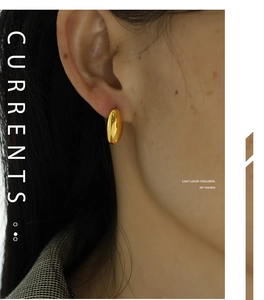 Close-up of minimalist polished gold bean stud earrings worn by a model