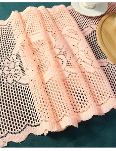 Close-up of pink crochet lace table runner with delicate mesh and wavy edge texture