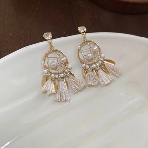 Detail of bohemian dreamcatcher earrings with gold rings, pearls, and soft tassels