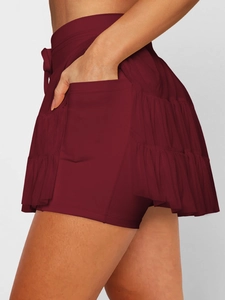 Detail view of burgundy pleated skort showing functional side pockets and layered mesh ruffles