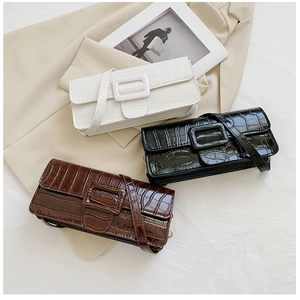 Flat lay of square crossbody bags with crocodile texture and decorative buckles