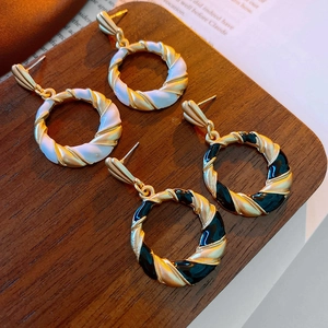 Detailed macro of vintage twisted gold hoop earrings with black and white enamel finish
