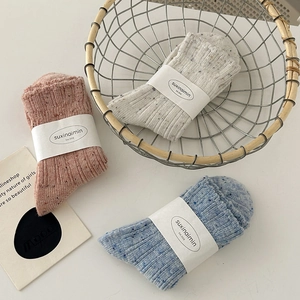 Three pairs of wool-blend knit socks in pink, beige, and blue with colorful speckled yarn