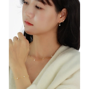 Close-up of elegant gold clover jewelry set worn by a model on a white background