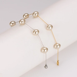 Elegant gold and silver pearl bracelets featuring large cream beads on a white pedestal