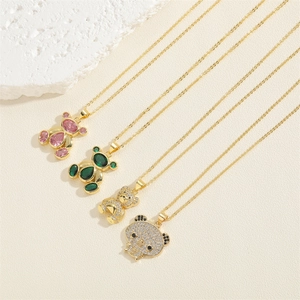 Gold bear pendant necklaces with emerald and pink zircon on a textured stone surface