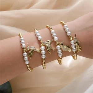 Bracelet élégant pour femme avec pendentif oiseau doré et perles blanches raffinées