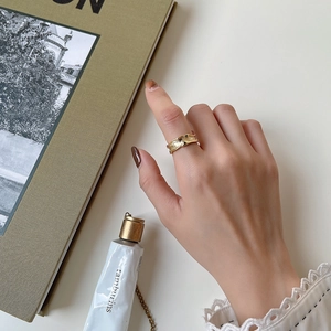 Close-up of golden irregular wavy ring with organic lava texture worn on female finger