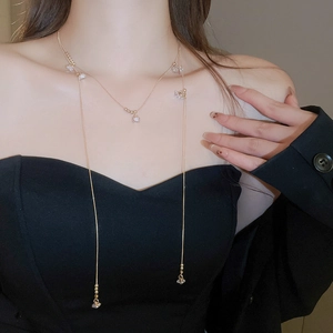 Détail du collier en Y doré orné de cristaux facettés porté par un mannequin chic