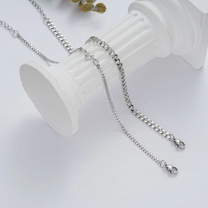Close-up of silver Cuban chain set with heart pendant on a decorative plaster pillar