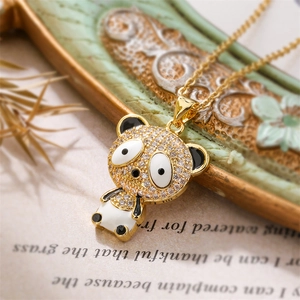 Macro detail of gold panda pendant with clear cubic zirconia and black enamel accents
