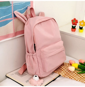 Close-up of pink school backpack with rabbit ears decoration on a desk setting