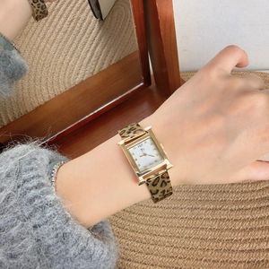 Wrist shot of golden square watch with leopard print strap reflected in a mirror