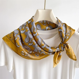 Detailed shot of a paisley pattern yellow silk scarf tied on a white hanger for styling