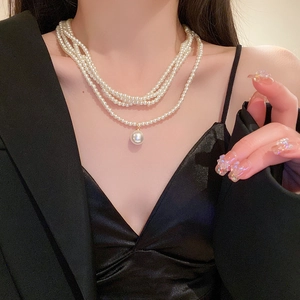 Elegant multi-layered baroque pearl necklace with pendant on a black blazer outfit