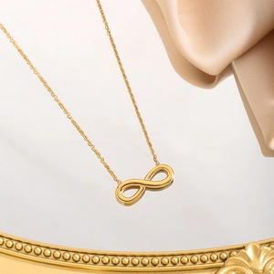 Elegant gold infinity pendant necklace on mirror background with champagne satin