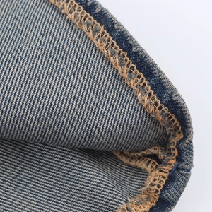 Detail of high-quality yellow stitching on indigo denim fabric of the midi dress