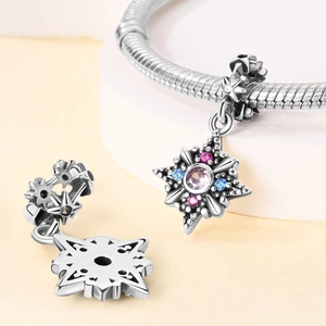 Macro detail of silver star pendant with pink and blue gemstones on a delicate bracelet