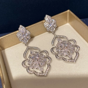 Detail of vintage silver earrings featuring intricate hollow floral design and zircons