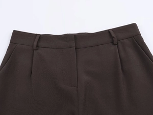 Détails du pantalon marron foncé montrant la taille, les passants et la texture en sergé