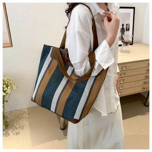 Detailed shot of striped canvas tote bag with reinforced leather corners and handles