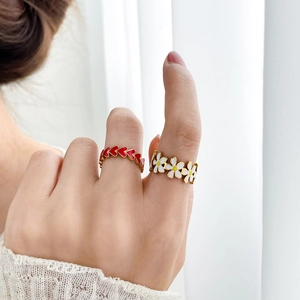 Close-up of golden enamel rings featuring red heart and white daisy floral patterns