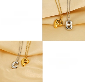 Detailed macro view of 3D bubble initial pendants in polished gold and silver steel