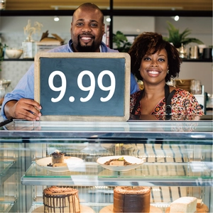 Bakery display showing assorted cakes and desserts with 9.99 price sign in a cafe setting