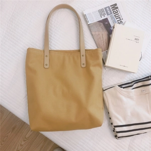 Detail of ginger canvas tote bag with beige leather handles and gold rivet accents