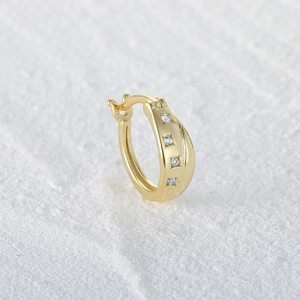 Macro shot of single gold S925 silver hoop earring with four inlaid cubic zirconia diamonds