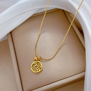 Détail macro du collier en titane doré avec pendentif caractère Fu et petite perle d'or