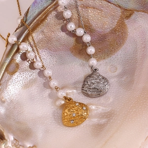 Close-up of 18K gold and silver shell pendants with rhinestones on pearl chains