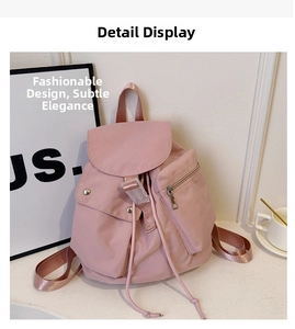 Detail of pink nylon backpack featuring a drawstring closure and side zipper pocket
