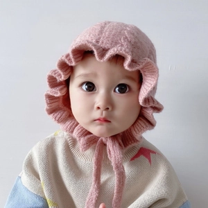 Detailed macro view of pink baby knit hat with ruffled edges and secure chin strap
