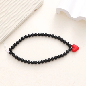 Detail of beaded phone wrist strap with black acrylic beads and red heart pendant
