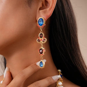 Detailed view of model wearing vintage luxury multi-gemstone teardrop pendant earrings