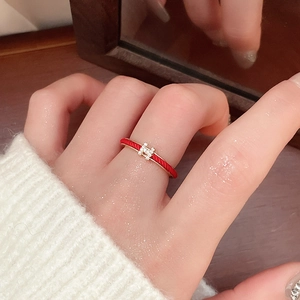 Close-up of a red enamel gold ring with H-shaped zircon inlay worn by a female model