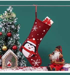 Roter Weihnachtsstrumpf mit Pinguin-Motiv und Geschenkbox-Detail am geschmückten Baum