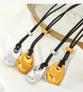 Detail of four teardrop pendants in gold and silver finish on adjustable black cords
