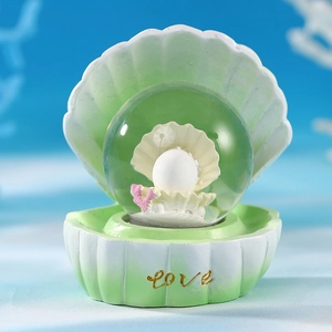 Detail of green shell crystal ball with white pearl, pink coral and gold love base