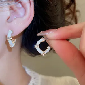 Elegant C-shaped bamboo stud earrings with white enamel and sparkling zircon accents