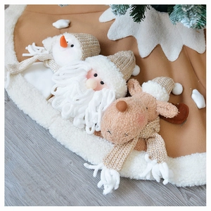 Close-up of a knitted Christmas tree skirt featuring 3D Santa, snowman, and reindeer dolls