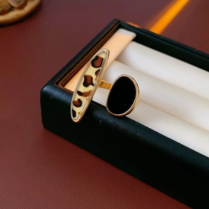Detail of retro leopard print and black drip glaze double-headed open ring on a display pad
