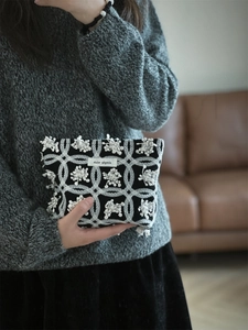Macro detail of vintage floral embroidery and brand label on a linen canvas makeup pouch