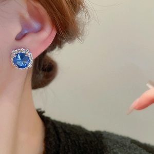 Detailansicht eines luxuriösen silbernen Ohrsteckers mit blauem Kristall und Diamanten