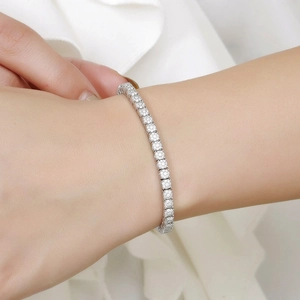 Detail shot of a four-claw moissanite tennis bracelet in silver on a model's wrist