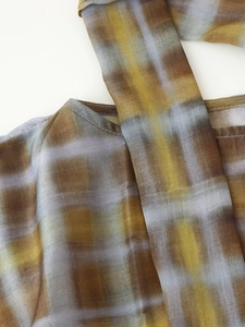 Detailed macro view of yellow and grey gradient plaid fabric showing fine stitching