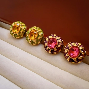 Macro detail of vintage style gold-plated oval earrings with green and purple enamel