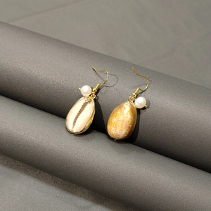 Detail of gold shell earrings featuring natural mother of pearl and white pearl accents