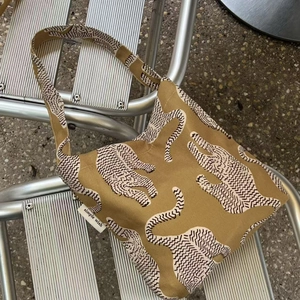 Sac fourre-tout en coton imprimé léopard posé sur une chaise en métal sur sol en pierre